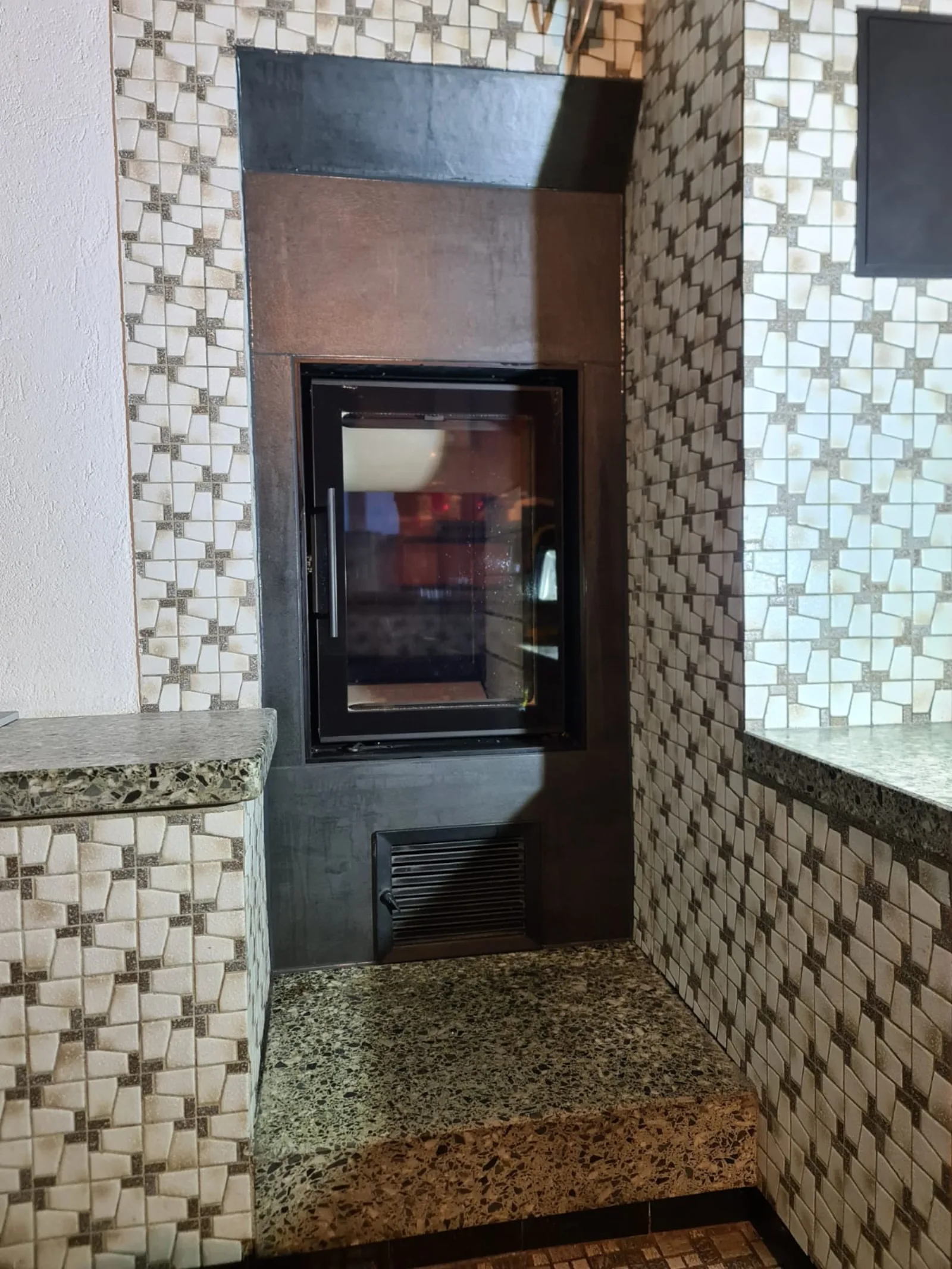 Cheminée mit Mosaikplatten und Granitbank